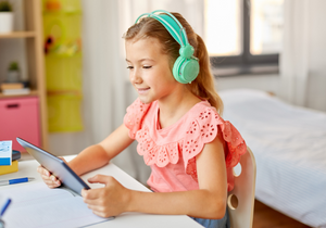 Child listening to audiobook with headphones and tablet