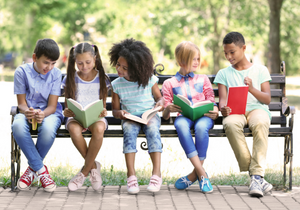 Children read together on a bench